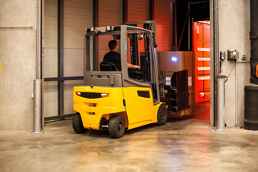 A Gebrüder Weiss warehouse employee uses a forklift to unload freight from a truck