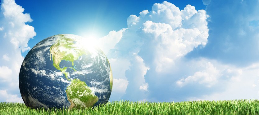 [Translate to United States of America:] An earth globe on grass surrounded by clouds to represent sustainability.