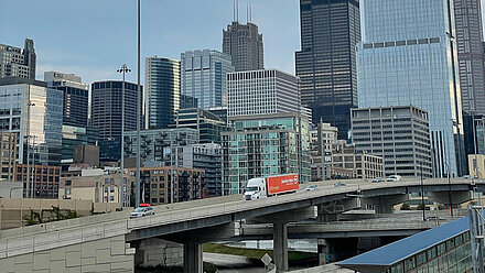 A Gebrüder Weiss truck on a highway ramp with the Chicago skyline in the background