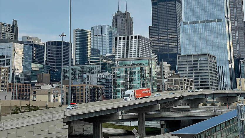 A Gebrüder Weiss truck on a highway ramp with the Chicago skyline in the background